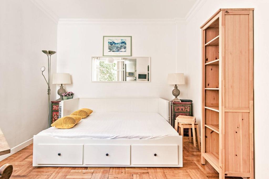 une chambre avec un lit blanc et une armoire en bois dans l'établissement FLEUR- Cosy Studio, 200 Promenade des Anglais et Negresco, wifi, climatisation- calme, à Nice