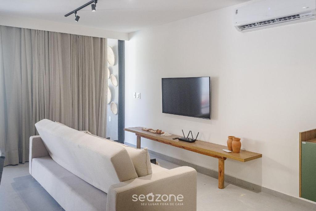 a living room with a couch and a tv on a wall at Apto Moderno c/ piscina e 3 suítes - VKA0115 in Tatuamunha