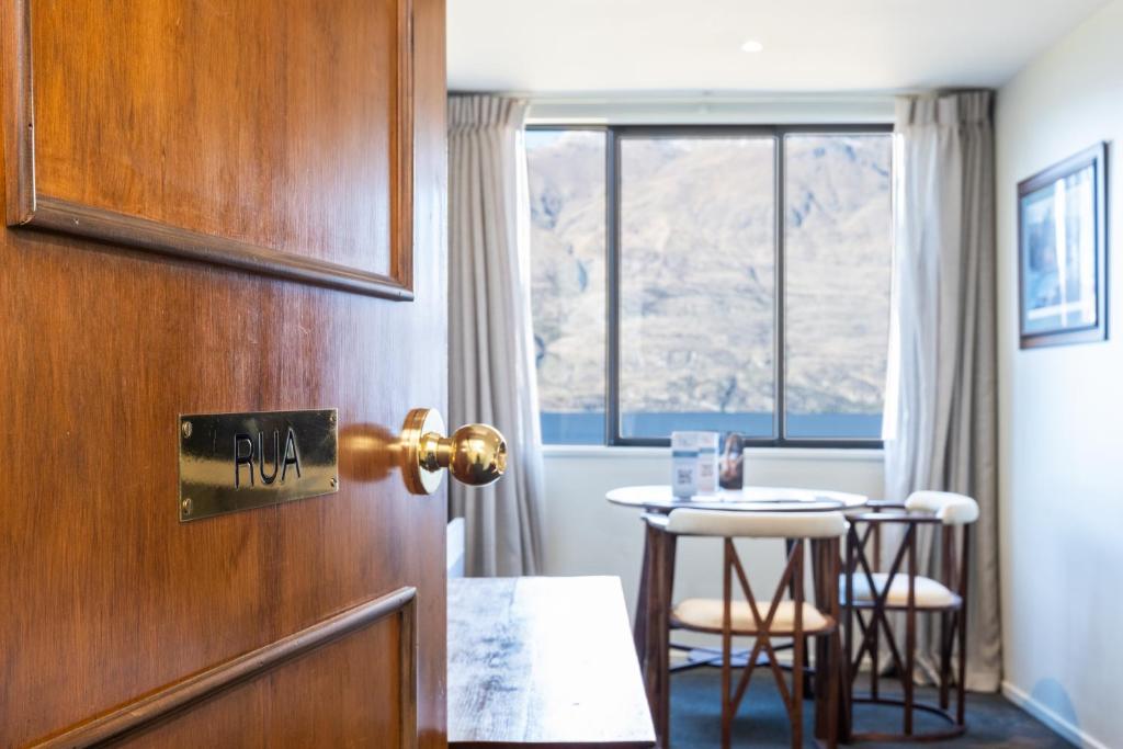 eine Tür zu einem Raum mit einem Tisch und einem kleinen Tisch in der Unterkunft Hidden Lodge Queenstown in Queenstown