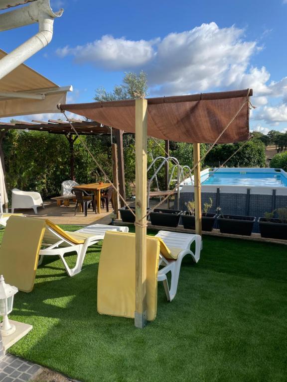 a patio with chairs and an umbrella and a pool at Quintinha do Zé da Lola in Silveiras