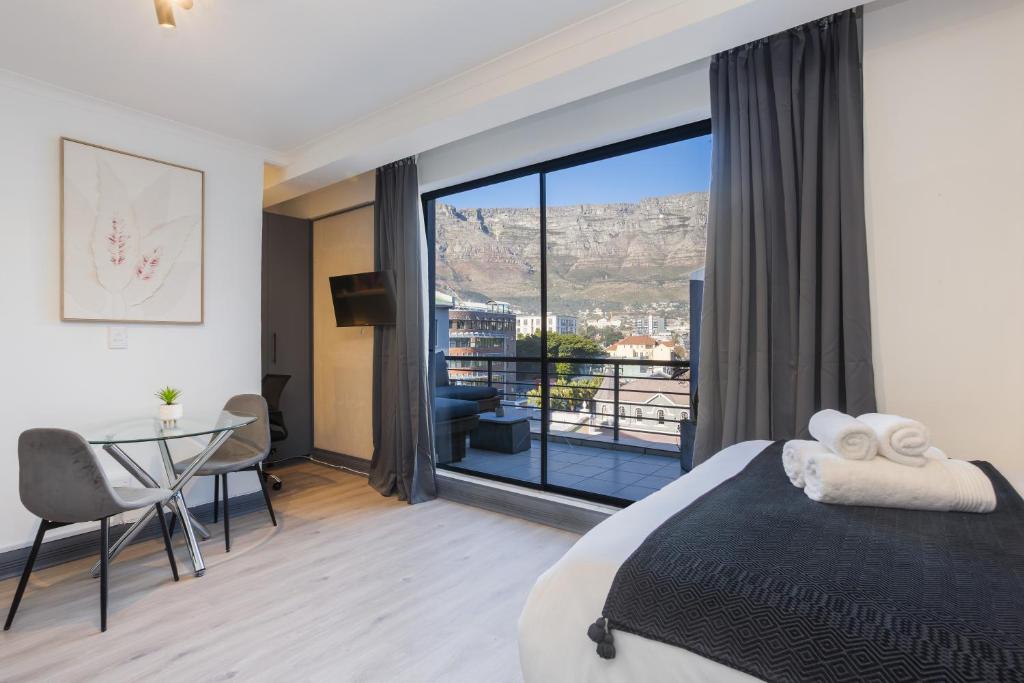 Cape Town Studio - Table Mountain Views, Gym, Free Parking, Free WiFi في كيب تاون: غرفة نوم بسرير وطاولة مطلة