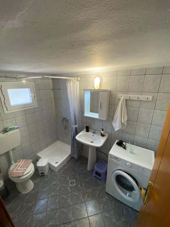 a bathroom with a toilet sink and a washing machine at Koutrakis apartment in Limenas