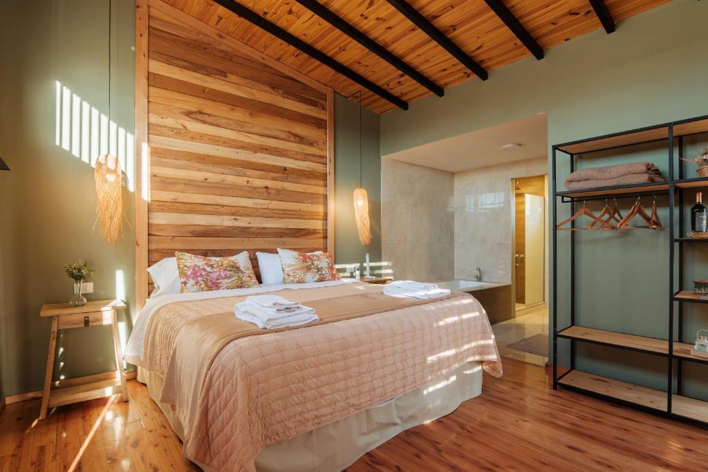 a bedroom with a large bed with a wooden wall at La Hijuela Cabañas de montaña in El manzano historico