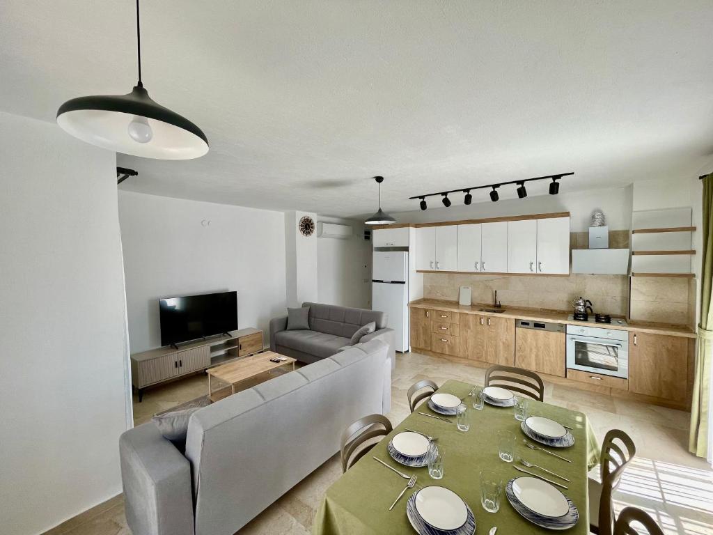 a living room with a dining table and a kitchen at Çam Tatil Evleri in Datca