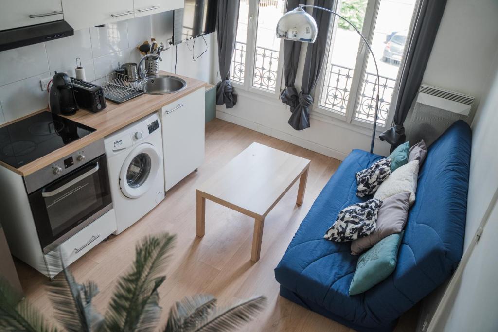 un salon avec un canapé bleu et une cuisine dans l'établissement Séjour famille ou pro accès rapide St-Lazare, à Argenteuil