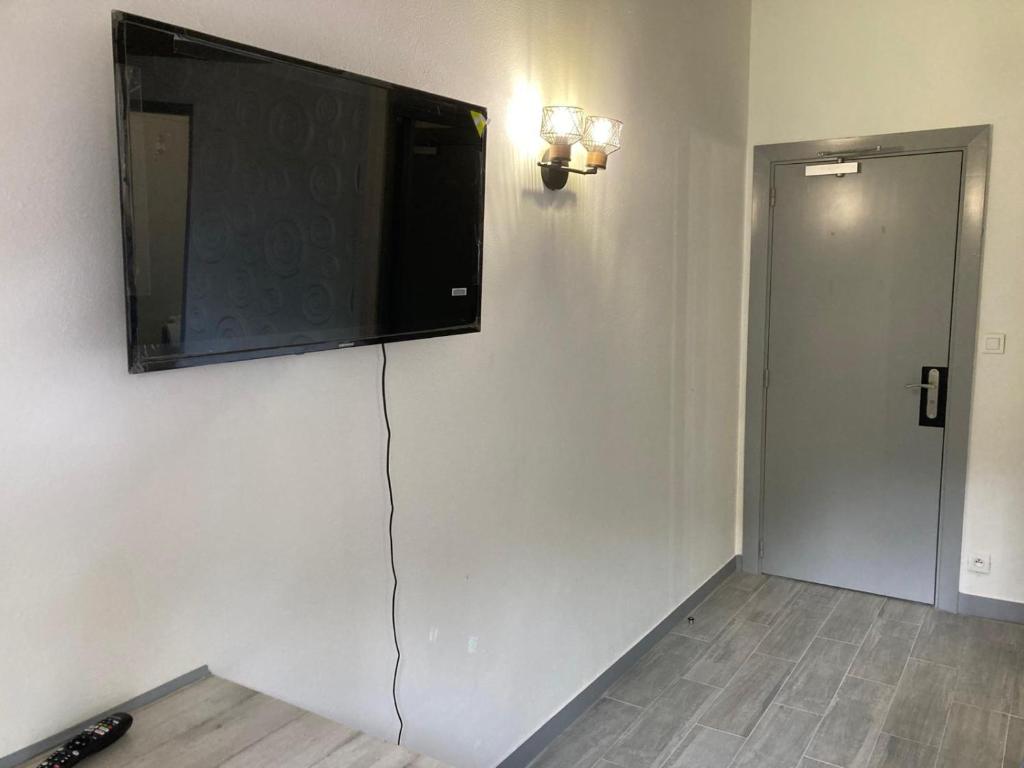a flat screen tv hanging on a wall at HSH France Chambre City 3 Proche de Disney in Meaux