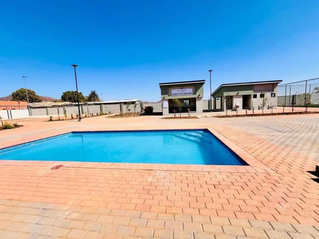 een blauw zwembad voor een gebouw bij LLL Apartments M6 in Khakalashwe