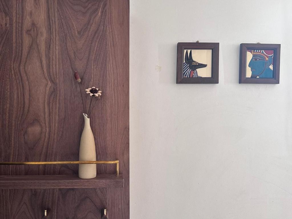 un vase sur une étagère avec trois photos sur un mur dans l'établissement City Center, cute cozy Appart, à Paris