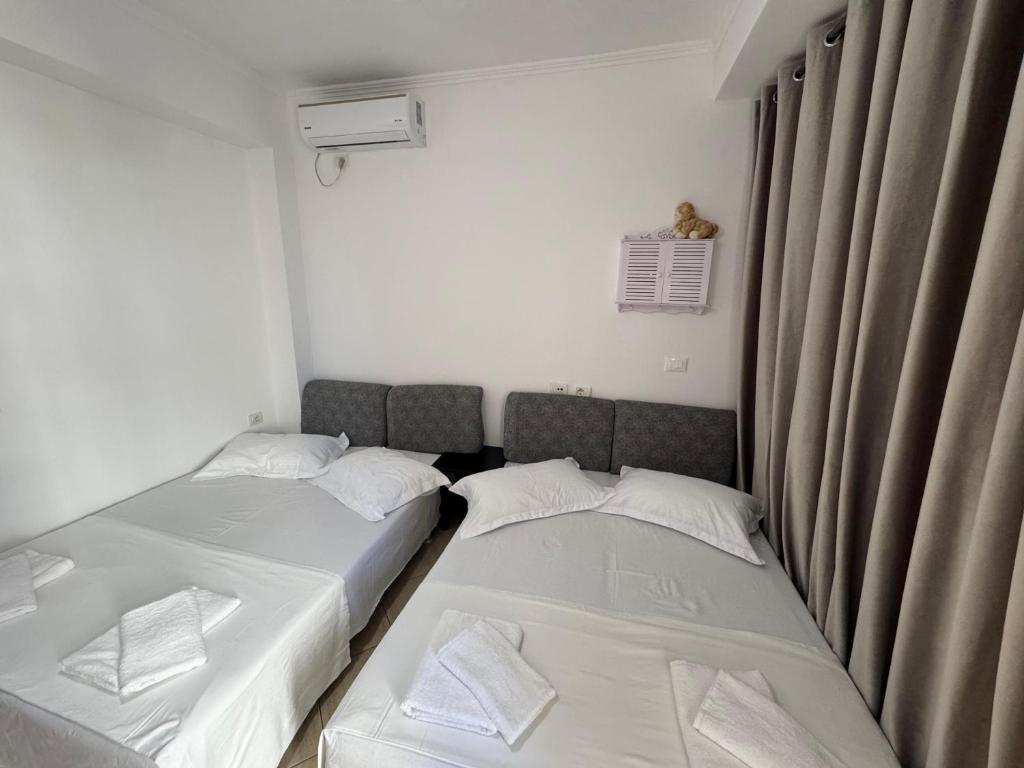 two twin beds in a small room with curtains at Hotel Barjami in Sarandë