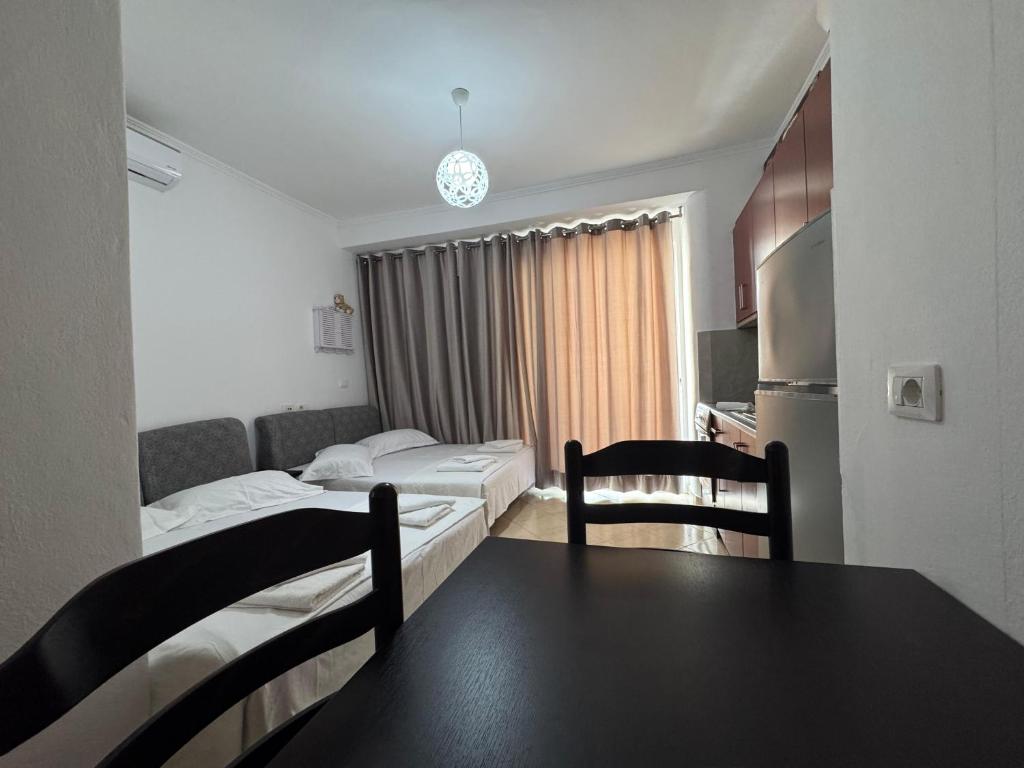 a room with two beds and a table and chairs at Hotel Barjami in Sarandë