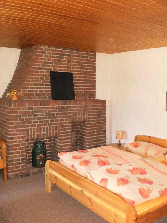 - une chambre avec une cheminée en briques, un lit et une télévision dans l'établissement Ländliche Ferienwohnung Mit Fahrradverleih, à Goosefeld