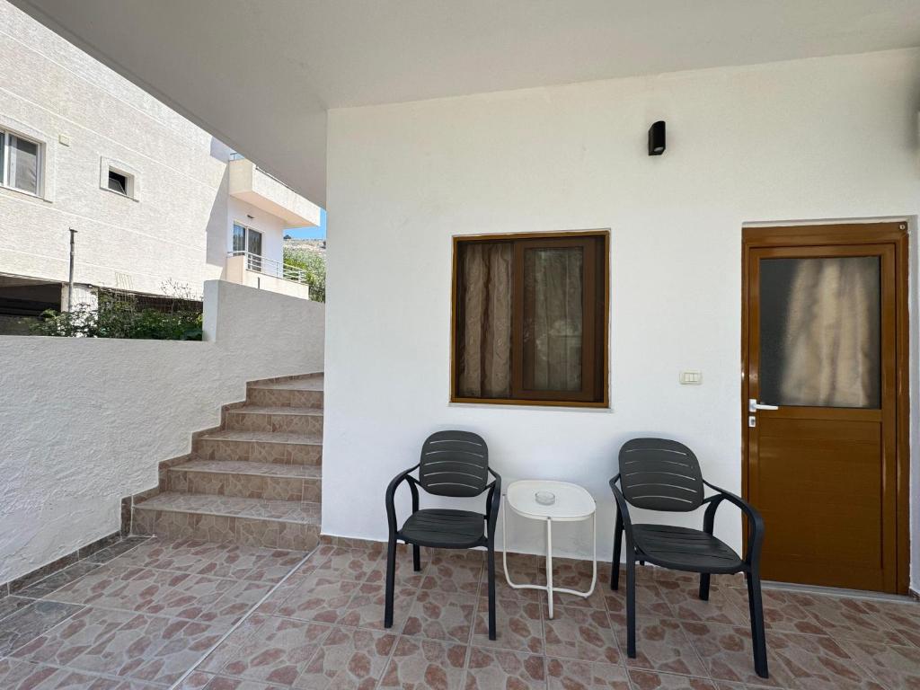 three chairs and a table in front of a building at Hotel Barjami in Sarandë