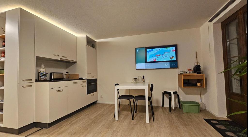 a kitchen with a table and a tv on the wall at Ferienwohnung GreenLook - Ferien am Lungernsee in Bürglen