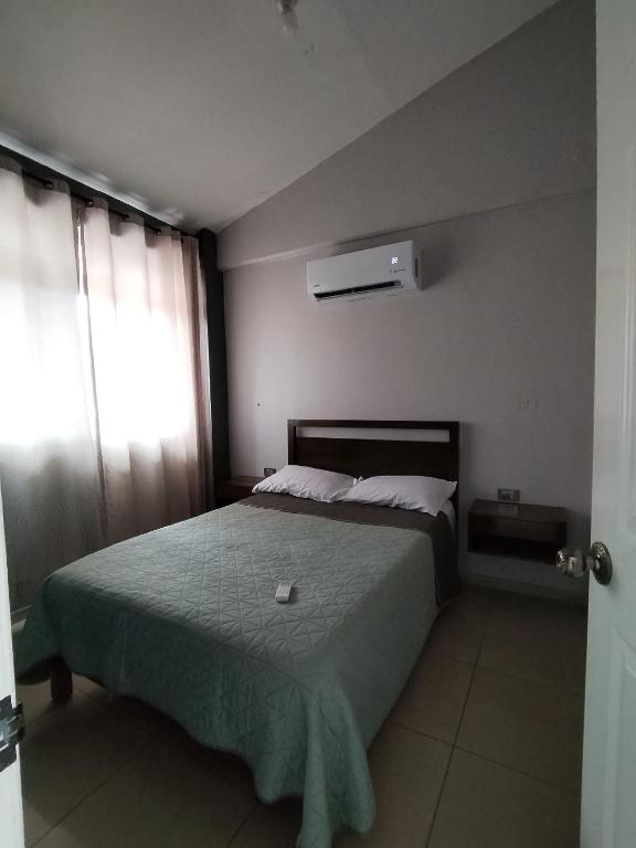 a bedroom with a bed with a green blanket and a window at La colina in San Roque