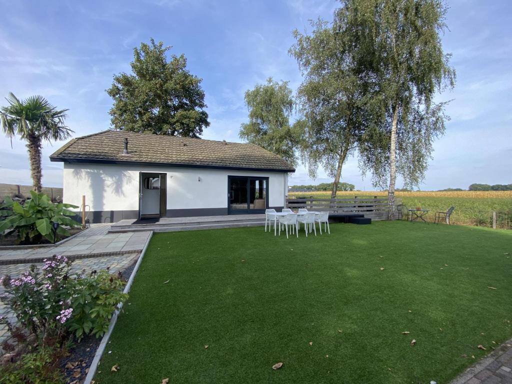 a small white building with chairs and a lawn at De Kolibrie in Garderen