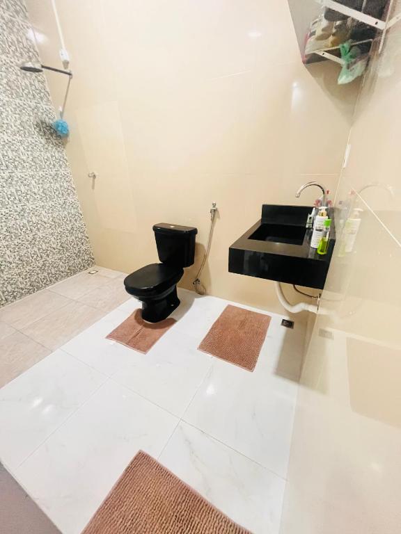a bathroom with a black toilet and a sink at Casa cidade nova in Ananindeua