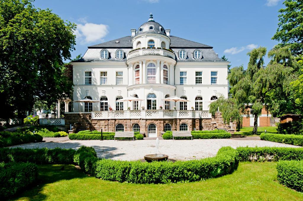 ein großes weißes Haus mit einem Brunnen im Hof in der Unterkunft Hotel Villa Dürkopp in Bad Salzuflen