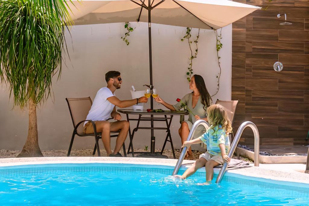 una famiglia seduta a un tavolo vicino a una piscina di Villa Kiin con piscina privada a 300 metros del mar a Playa del Carmen