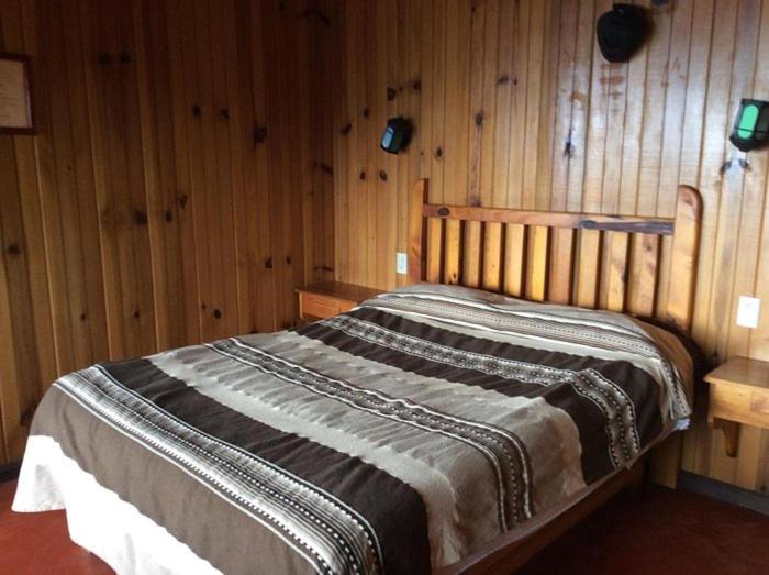 a bed in a room with wooden walls at Las Bromelias in Coconuco