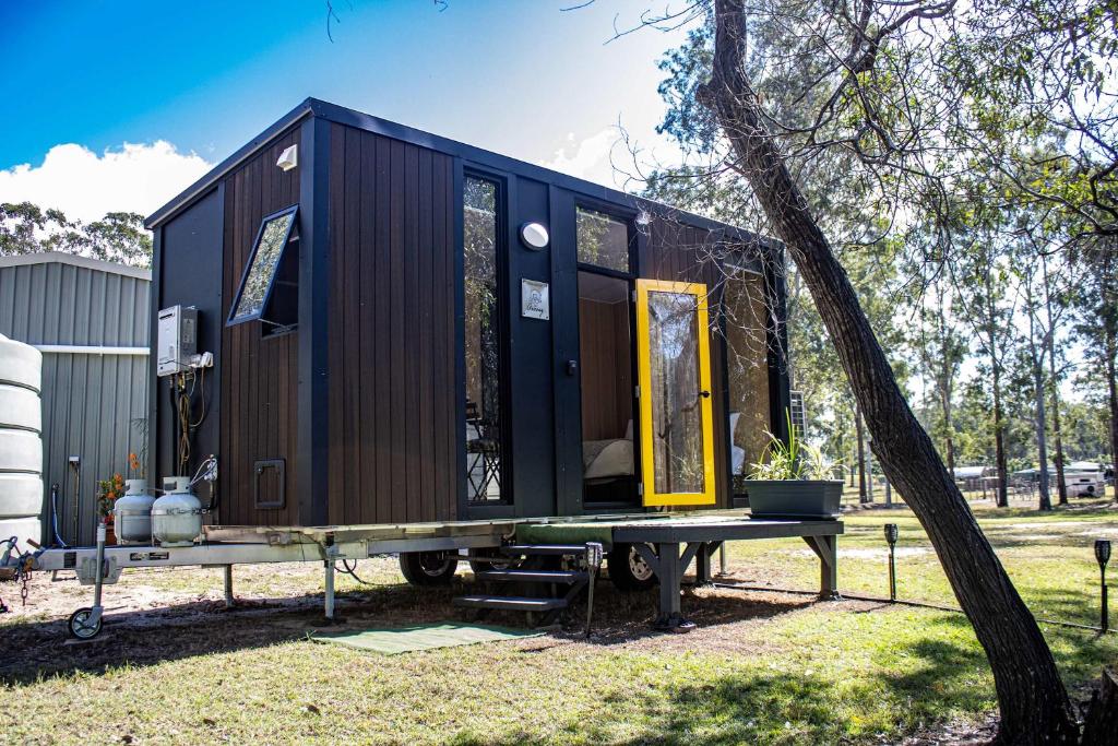 a black tiny house sitting on a table next to a tree at JJJ's Ranch Farm 1 by Tiny Away in Koolboo
