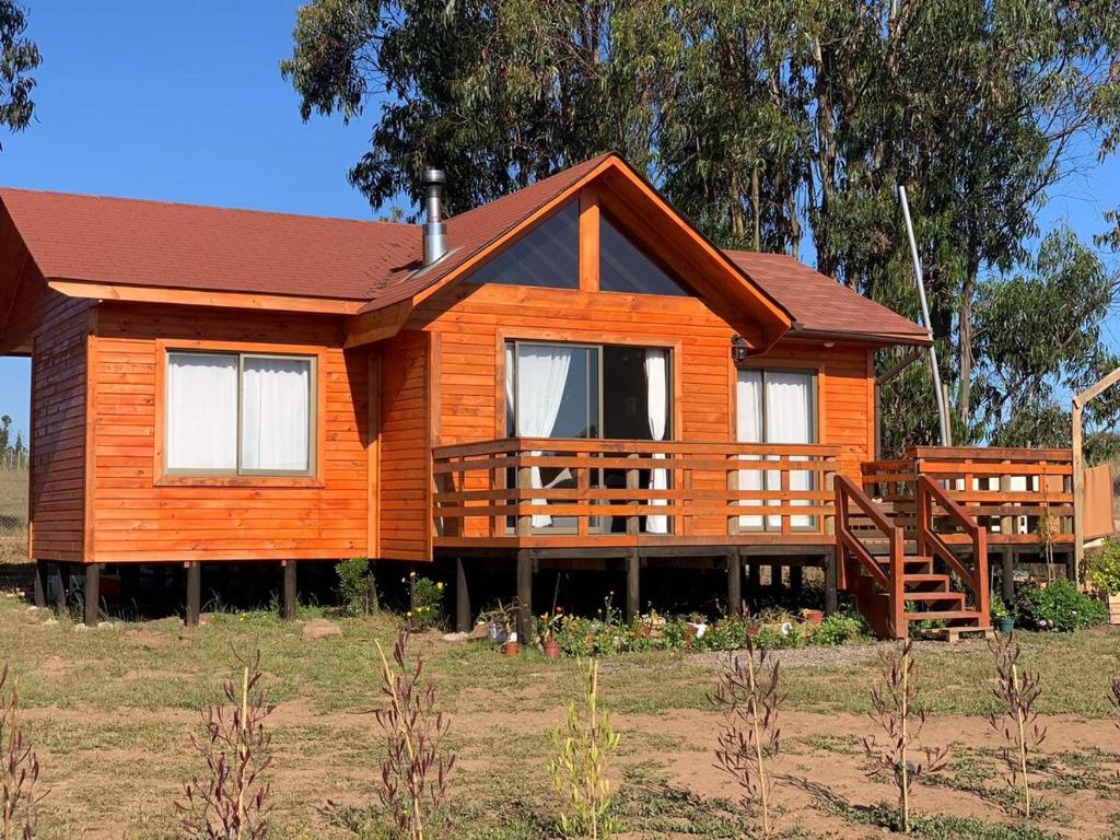 a large wooden house with a porch in a field at Cabaña Amelia de Tunquen in San Antonio