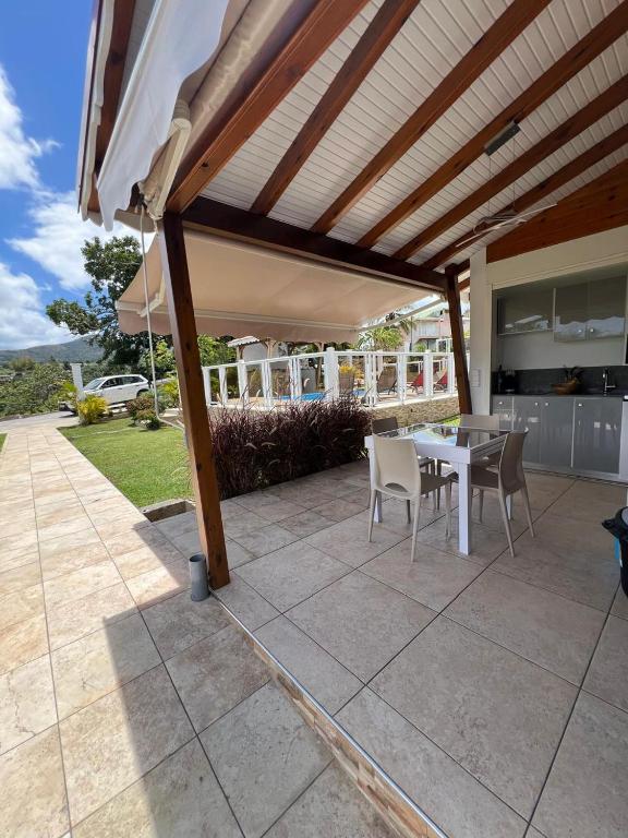 a patio with a table and chairs under awning at Le Doux Paradise- GOYA in Sainte-Rose