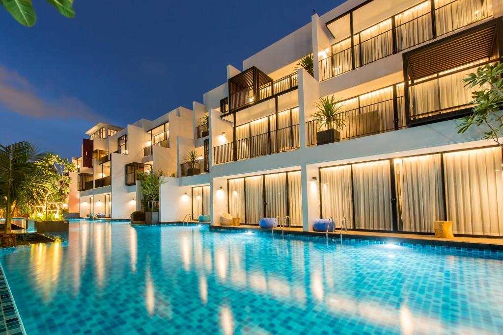 una piscina frente a un edificio por la noche en Asira Boutique HuaHin, en Hua Hin