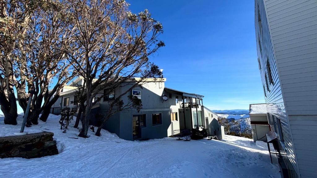 a house in the snow next to a building at Alpine Heights 11B in Mount Hotham