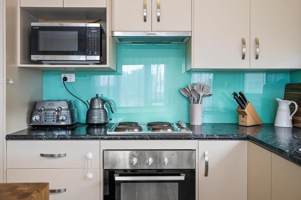 une cuisine avec une cuisinière et un micro-ondes dans l'établissement Silver Myrtle Shack - Aldinga Beach - C21 SouthCoast Holidays, à Aldinga Beach