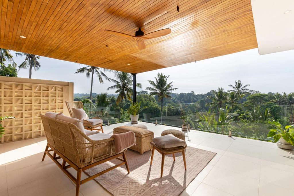 a living room with chairs and a ceiling fan at IBU The Sanctuary by OXO in Ubud