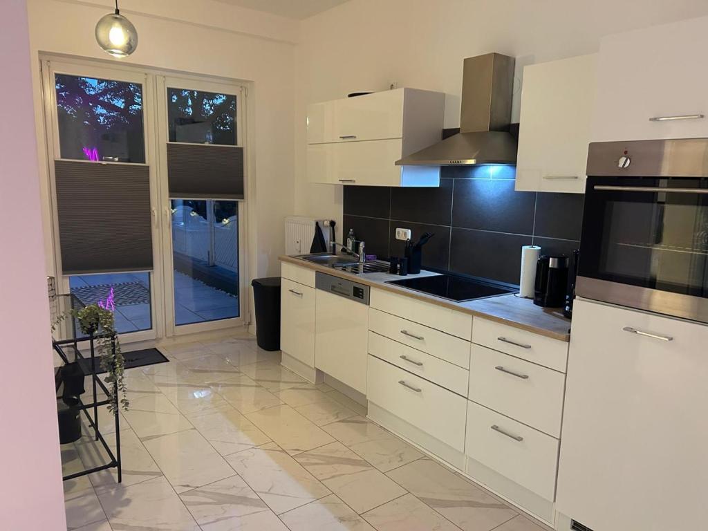 a kitchen with white cabinets and a large window at Superior XL - 110qm - 9 Personen Central Rooftop - 20 min to Hamburg in Elmshorn