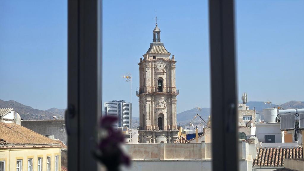 a view of a clock tower from a window at Felix Saenz Boutiques Suites by Del Parque Flats in Málaga