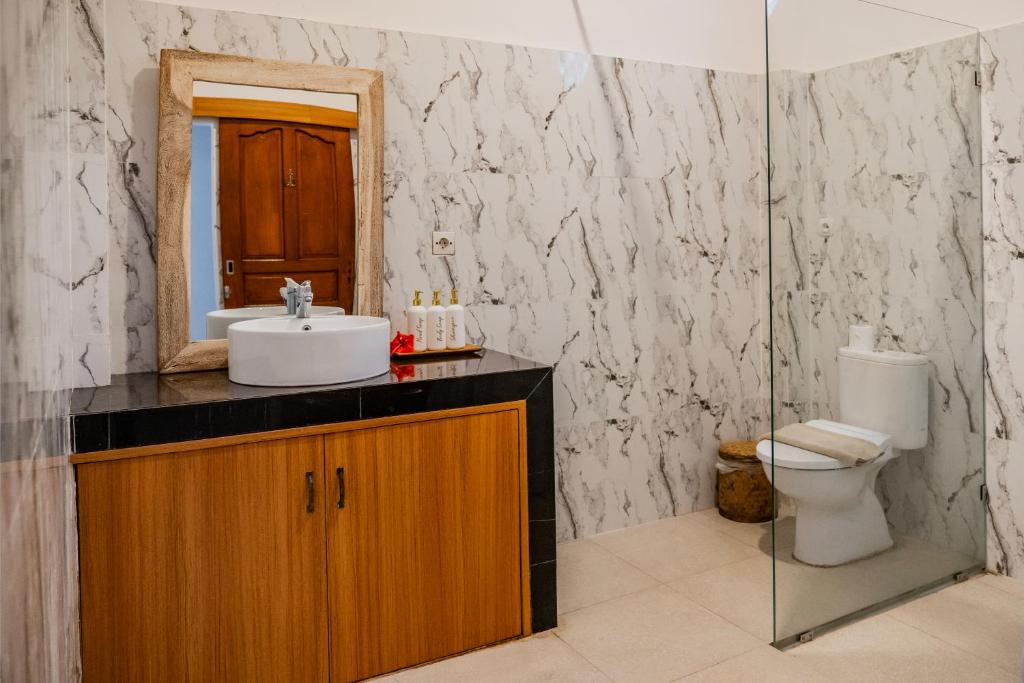 ein Badezimmer mit Waschbecken, Toilette und Spiegel in der Unterkunft Umah Kita Villa in Seminyak