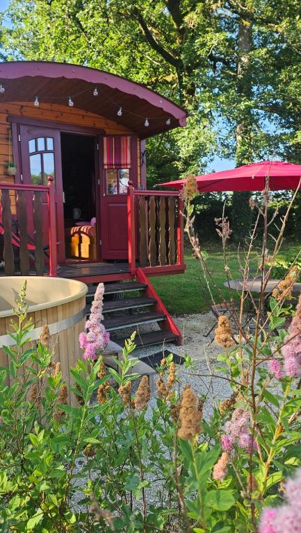 une petite cabane dans un jardin avec un porche dans l'établissement Le Roulottes du Petit Gouffre de Padirac avec Spa, à Padirac