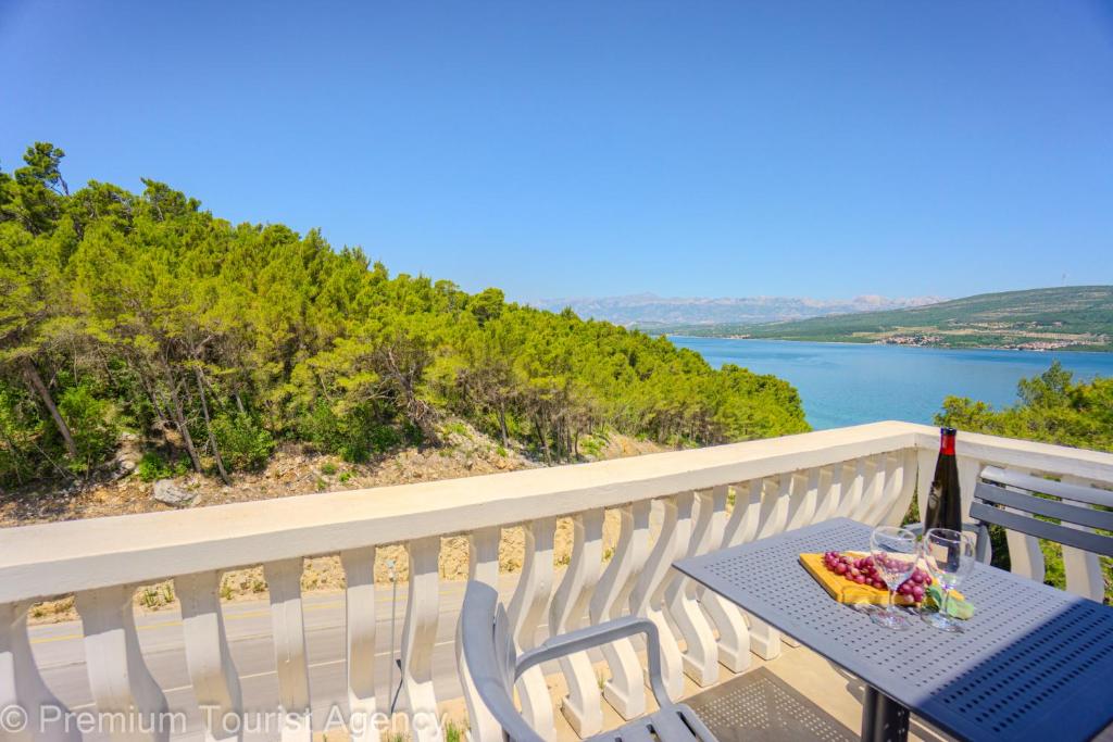 a table and chairs on a balcony with a view of the water at Green Haven Sea & Forest Apartments in Donji Karin