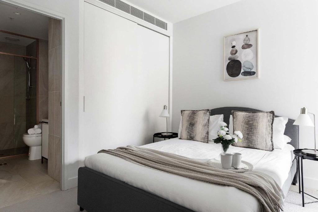 Un dormitorio blanco con una cama con un jarrón de flores. en A Cozy 2BR Apt Right on Buzzing Chapel Street, en Melbourne