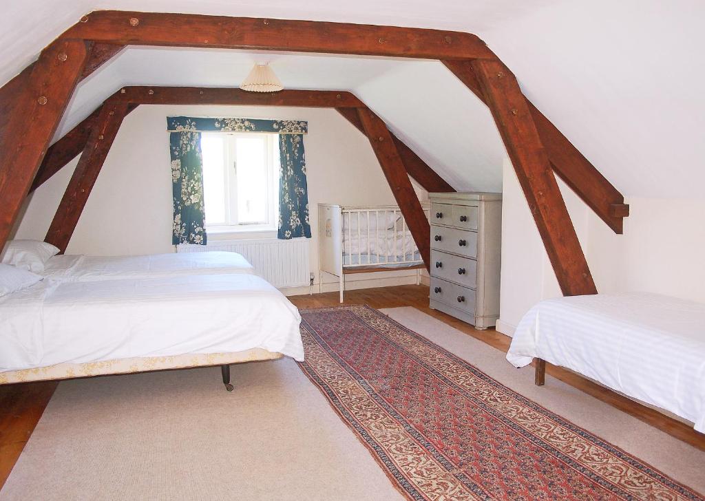 a attic bedroom with two beds and a window at Old Orchard Cottage in Colyton
