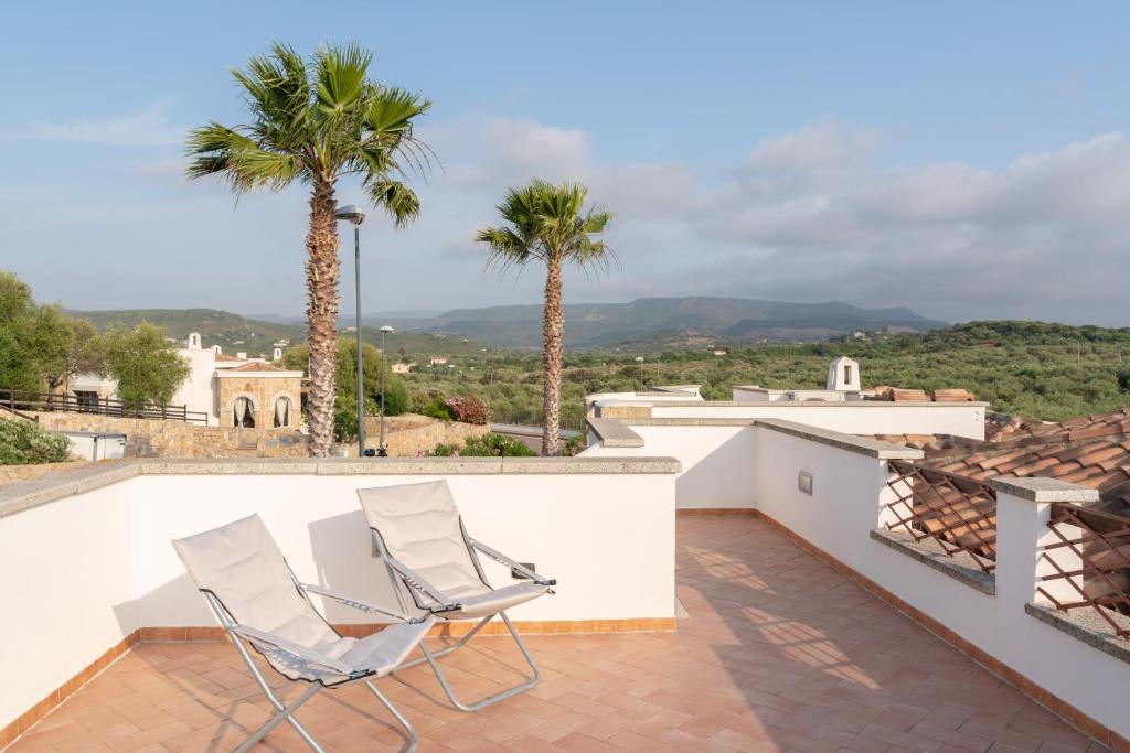 two chairs on a balcony with palm trees at New Vista Blu Alghero in Alghero