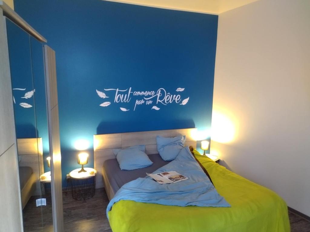 een slaapkamer met een bed met een blauwe muur bij L'appart Millau Centre-Ville - Gite in Millau