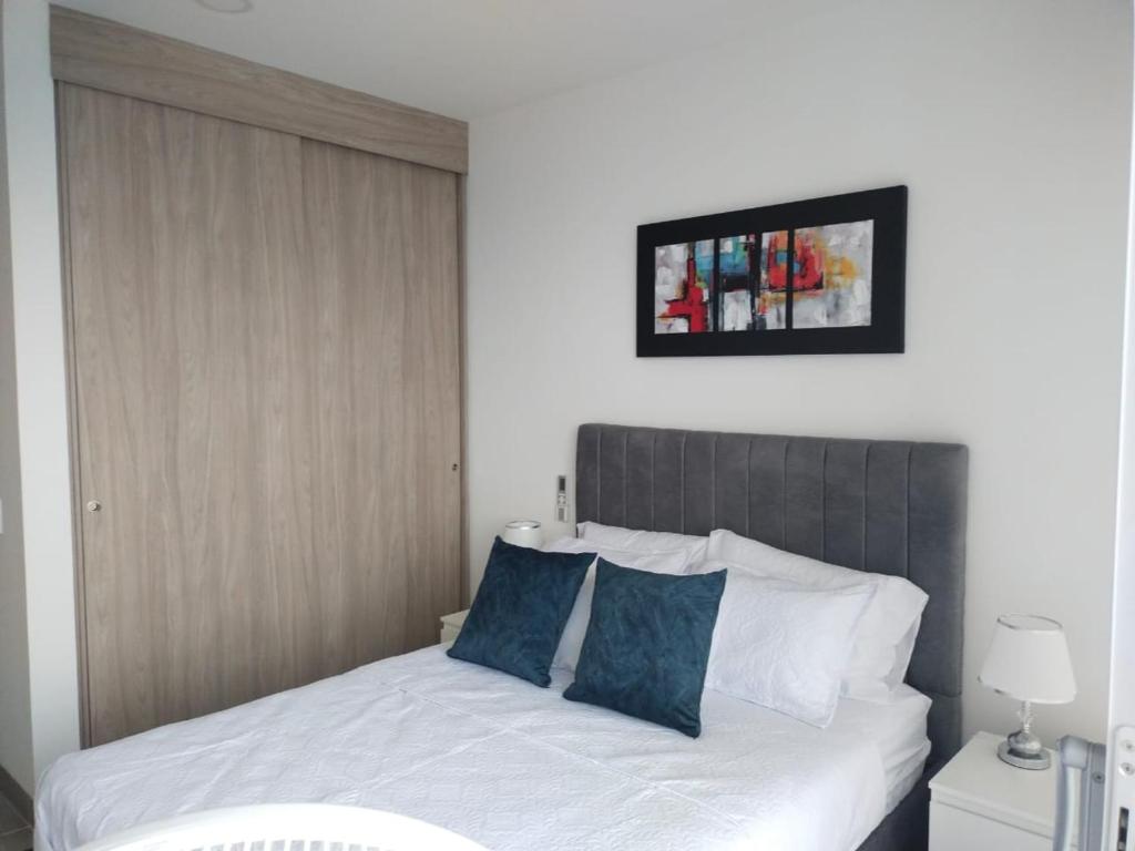 Estrene en Santa Marta vía Barranquilla a 10 minutos aeropuerto, acceso y vista al mar في سانتا مارتا: غرفة نوم بسرير ابيض مع مخدات زرقاء