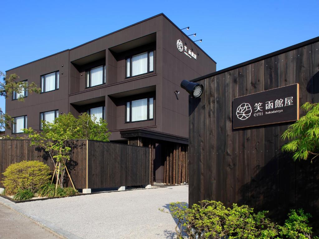 brązowy budynek z znakiem przed nim w obiekcie Yunokawa Onsen Emi Hakodateya w mieście Hakodate