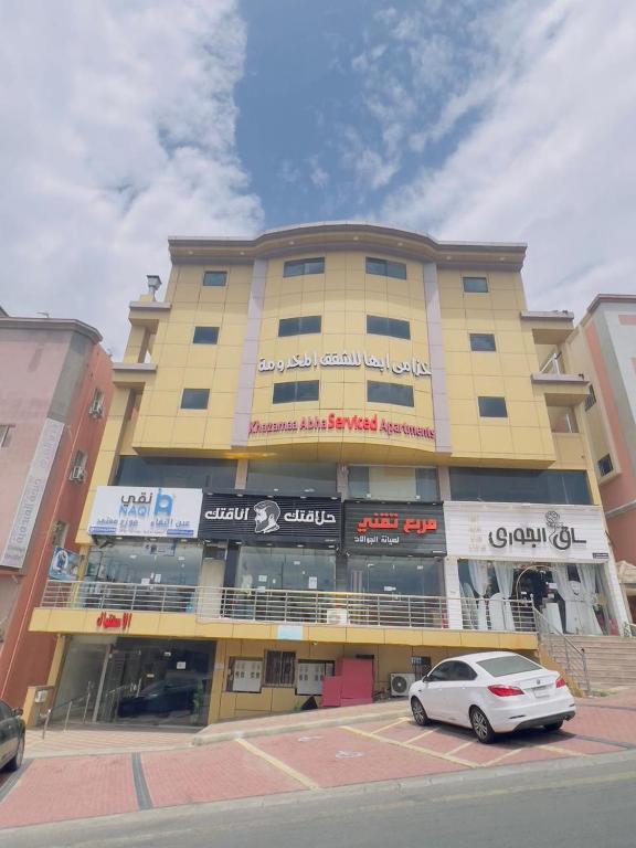 a yellow building with a car parked in front of it at خزامى ابها للشقق المخدومة in Abha