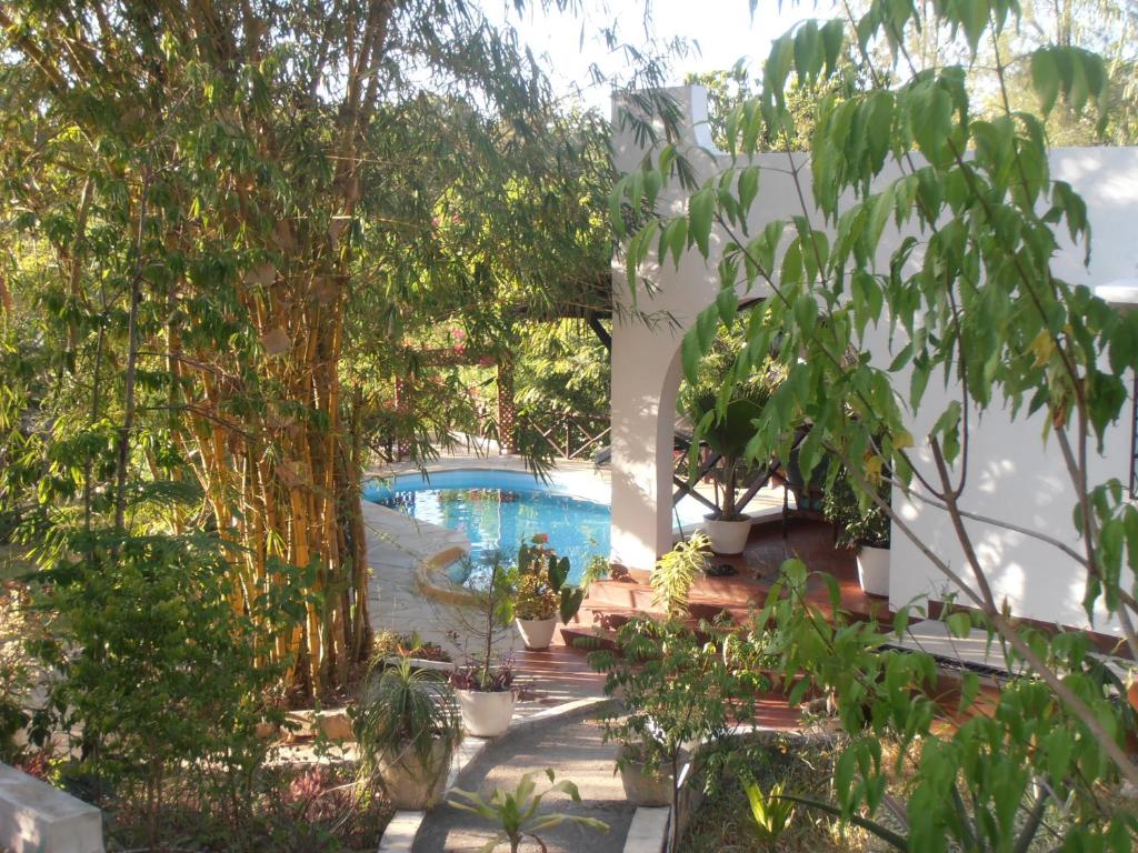 un jardín con piscina y árboles en Tropical Garden House en Kilifi