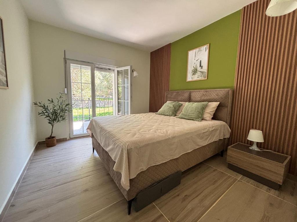 a bedroom with a bed with green walls and a window at Apartments Giardino Mediterraneo in Petrovac na Moru