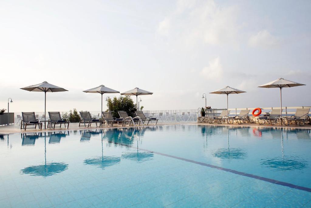 a large swimming pool with chairs and umbrellas at Asteris Hotel in Skala Kefalonias
