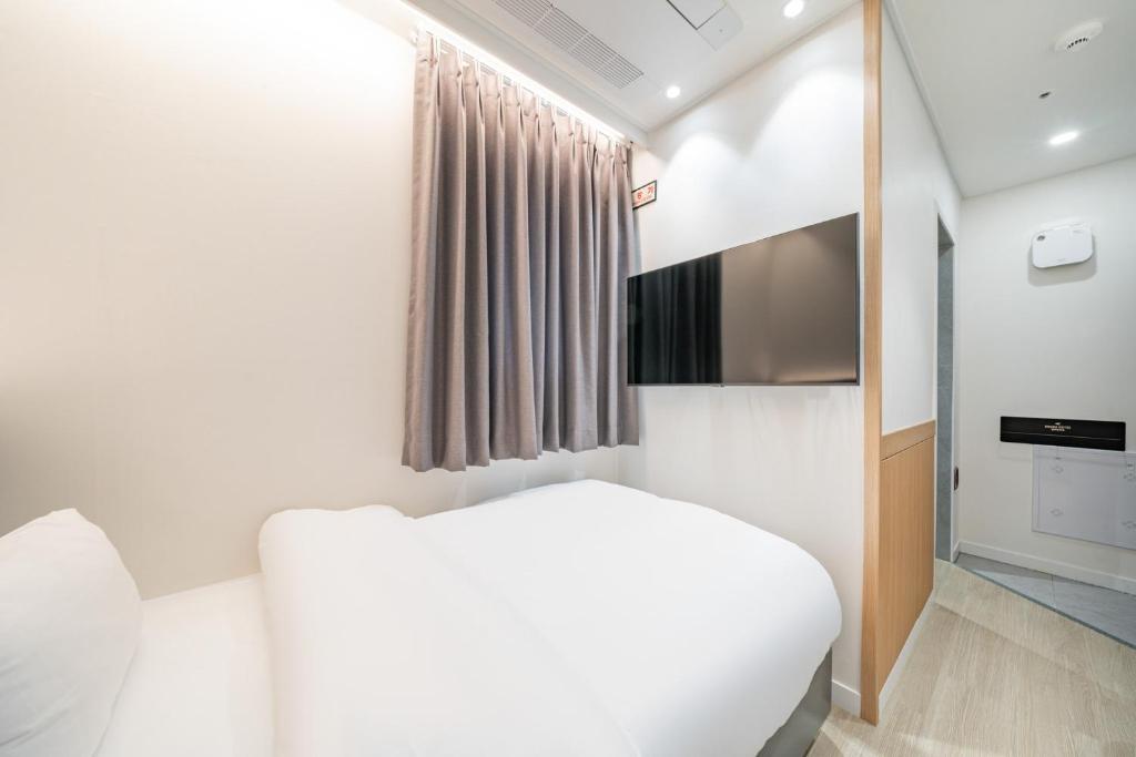 a bedroom with a white bed and a window at Hound Hotel Mokpo Peace Plaza in Mokpo