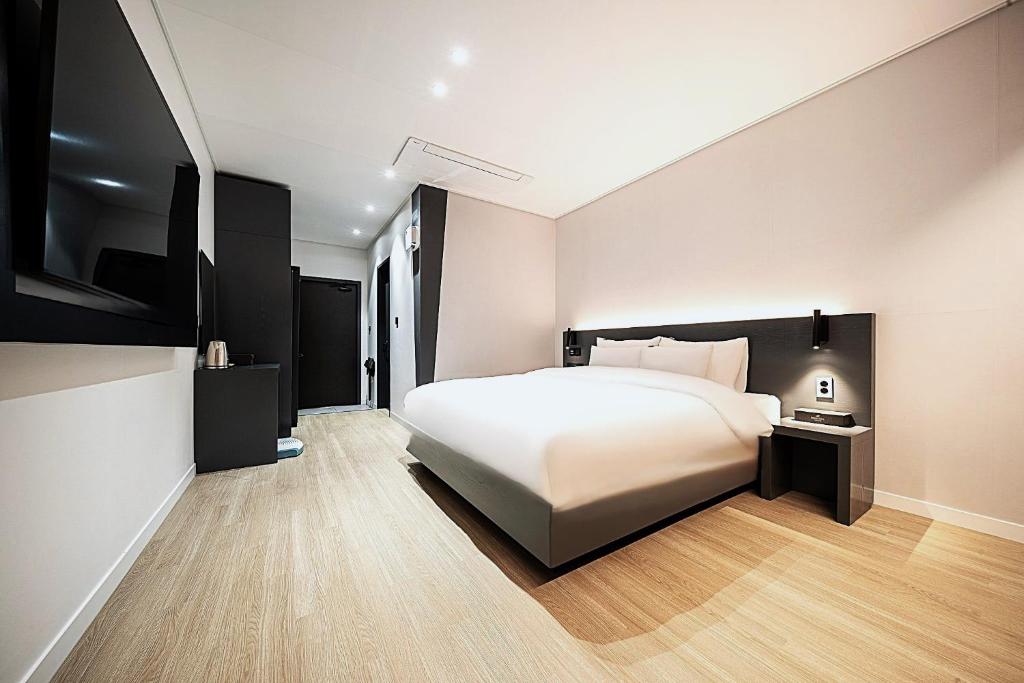 a bedroom with a large white bed and wooden floors at Hound Hotel Mokpo Peace Plaza in Mokpo