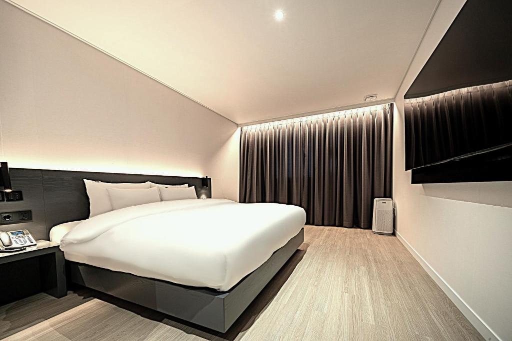 a bedroom with a large white bed and a window at Hound Hotel Mokpo Peace Plaza in Mokpo