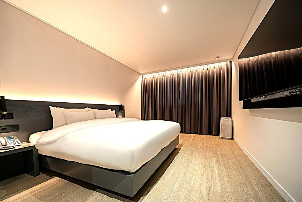 a bedroom with a large white bed and a window at Hound Hotel Mokpo Peace Plaza in Mokpo