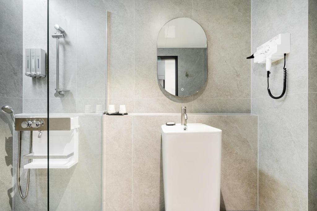 a bathroom with a shower and a toilet and a mirror at Hound Hotel Mokpo Peace Plaza in Mokpo